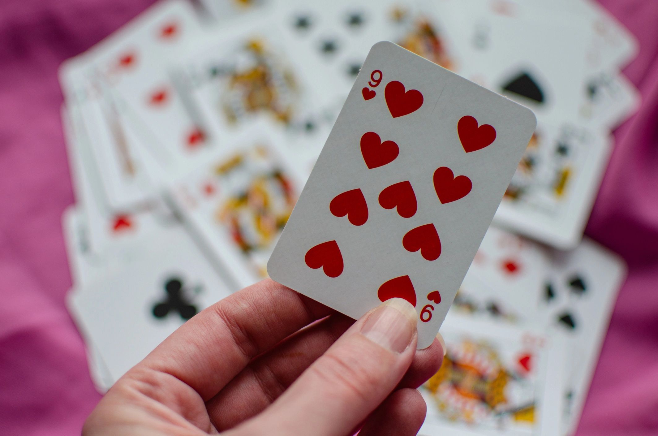Playing cards scattered across a pink background